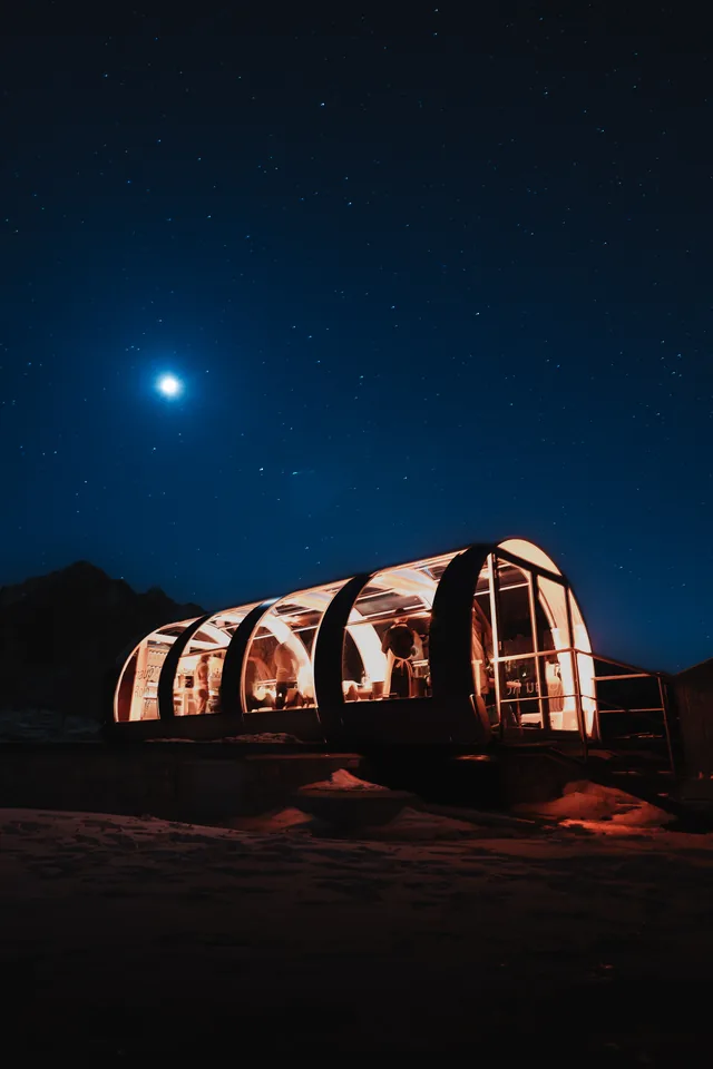 El espacio de bulthaup Grandvalira iluminado de noche sobre la nieve